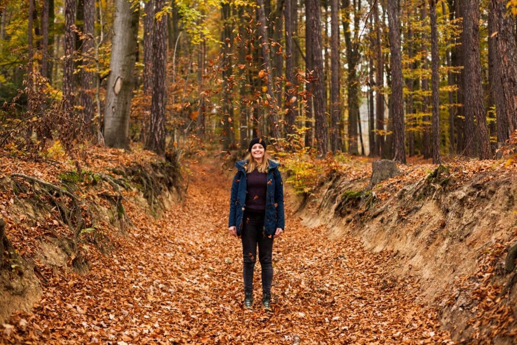 Mujer haciendo senderismo en un bosque con hojas en Otoño