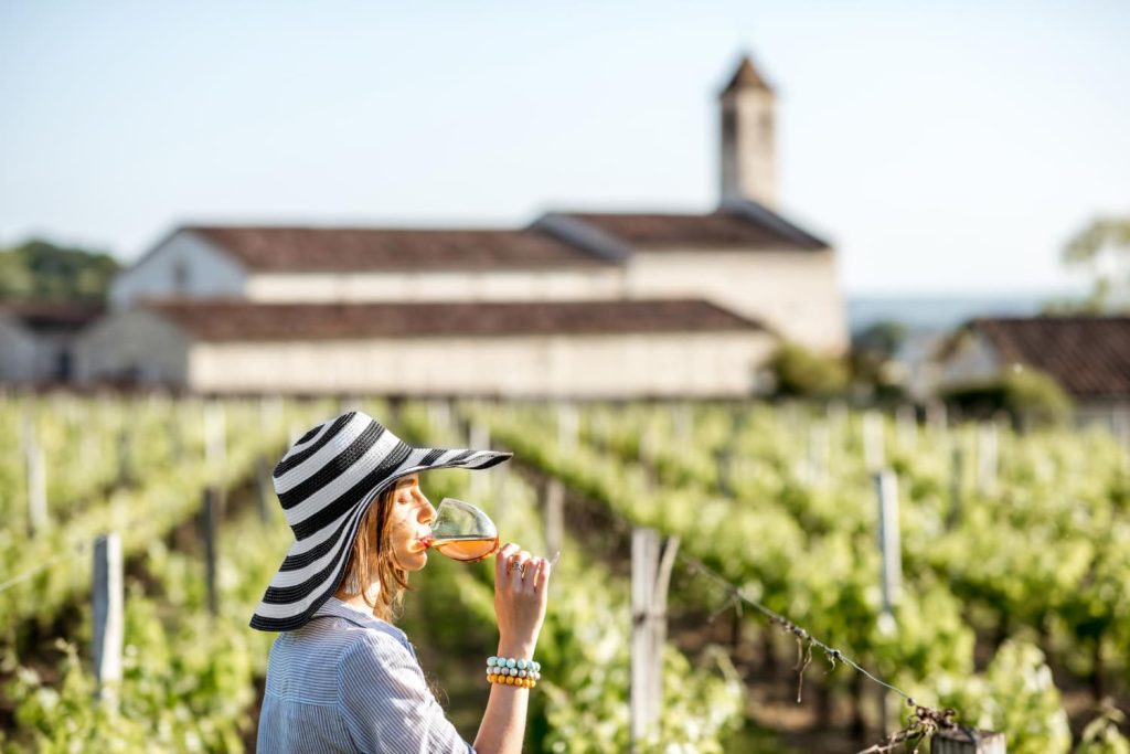 Mujer bebiendo una copa de vino en un viñedo